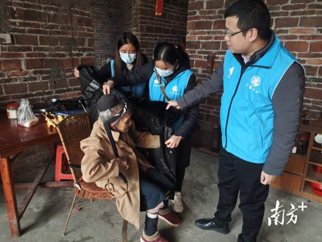 連南瑤族自治縣香坪鎮社工站為困難高齡老人送去御寒棉衣，并幫老人穿上棉衣。